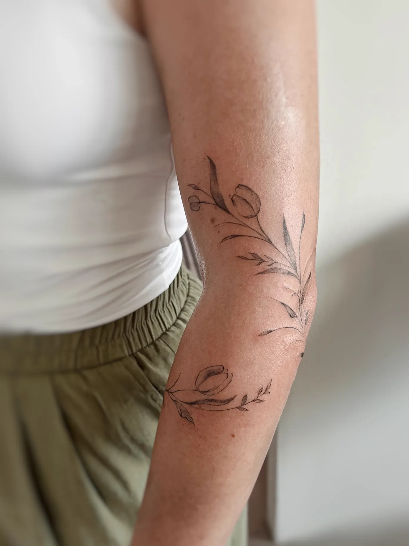 Jemné tetování tulipánů ovíjející loket